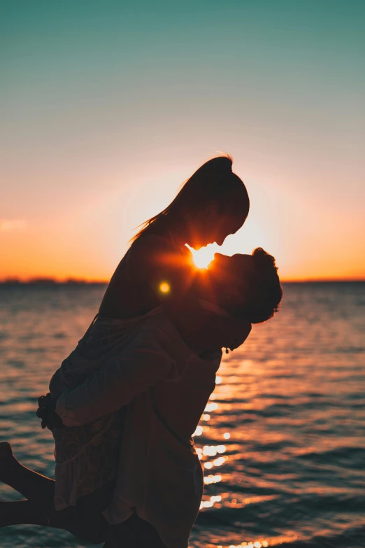 a couple kissing in front of the ocean