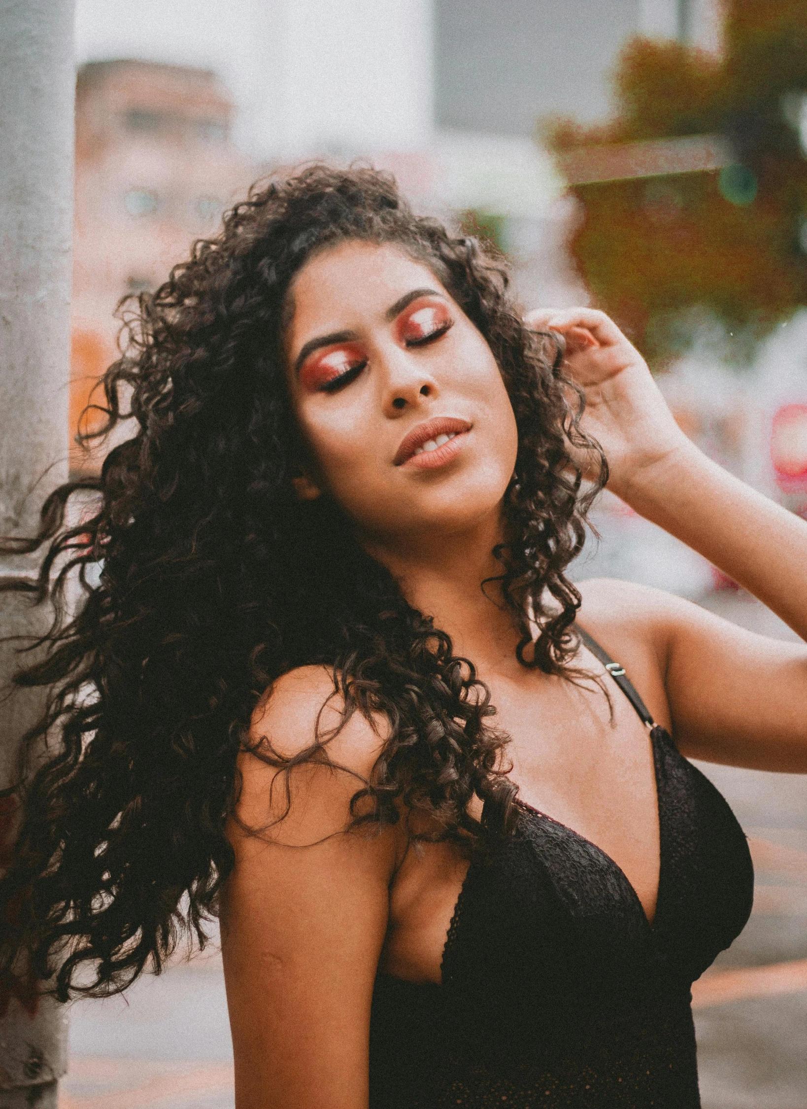 a beautiful young woman with long curly hair standing near a pole