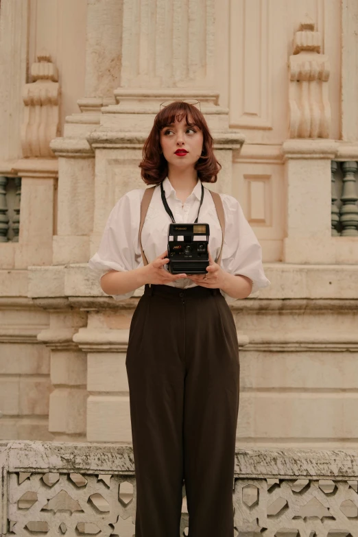 a lady wearing all white holding a camera and wearing an suspender