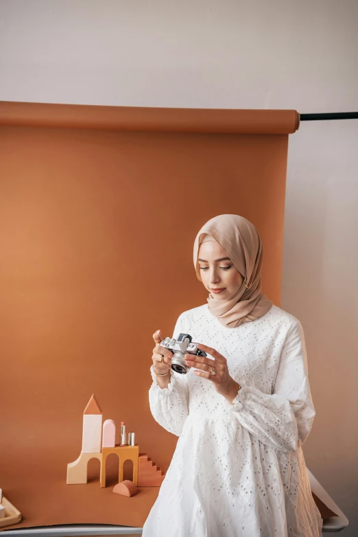 a woman in white outfit holding a cup and a camera