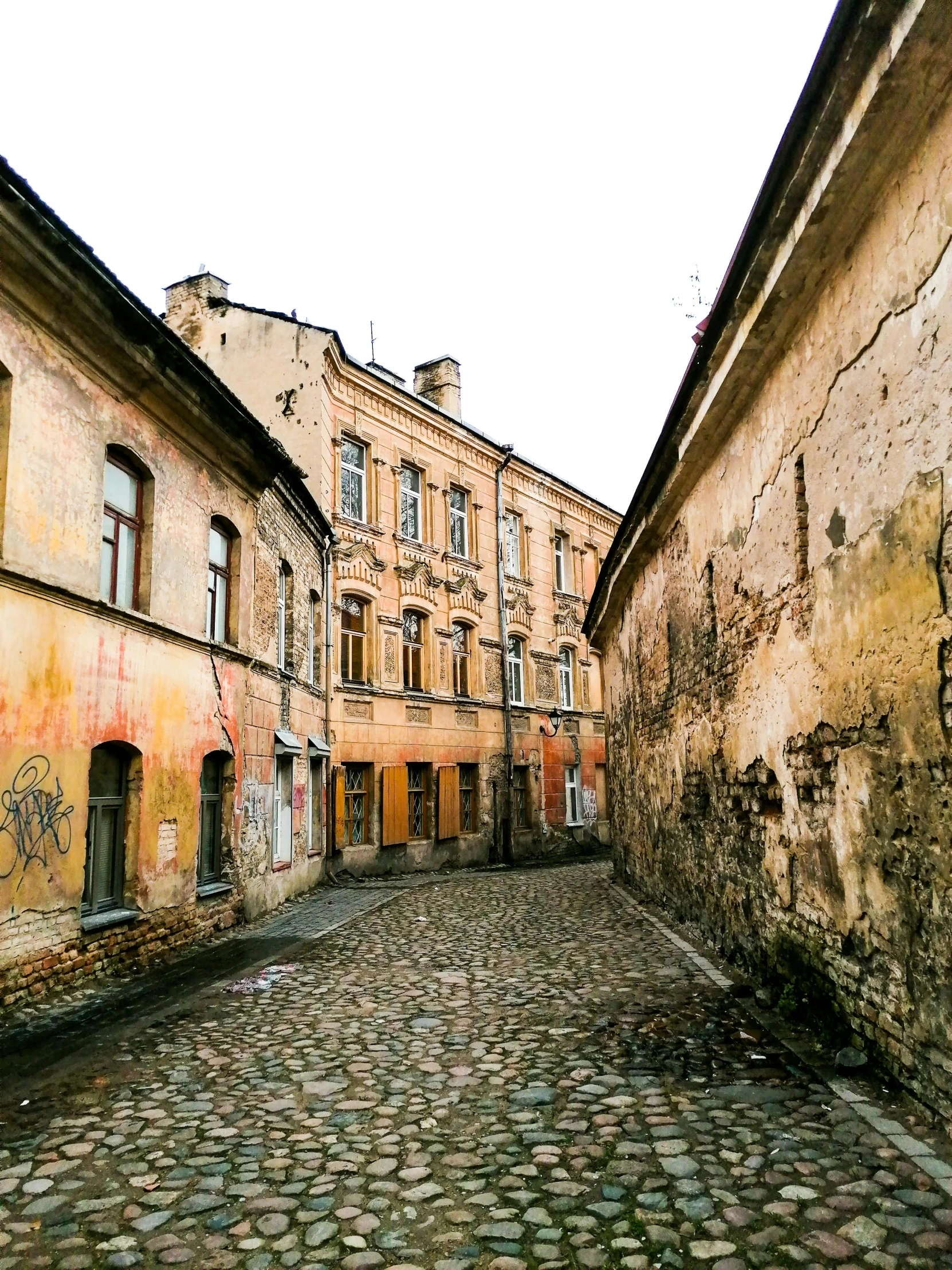 the buildings are brick and two windows are on one side of the street