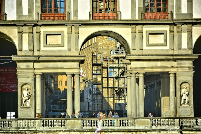 people standing under the scaffoldings outside a large building