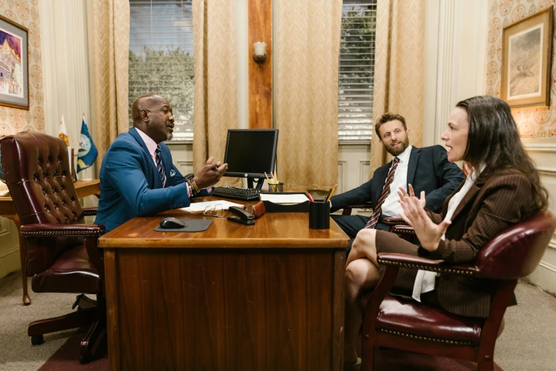 three business people in suits are sitting at a table
