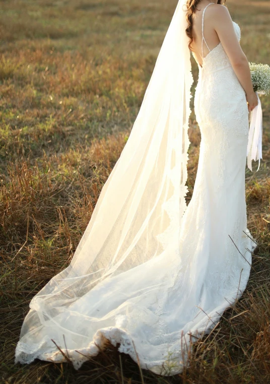 a woman in white wedding dress with veil looking back at her dress