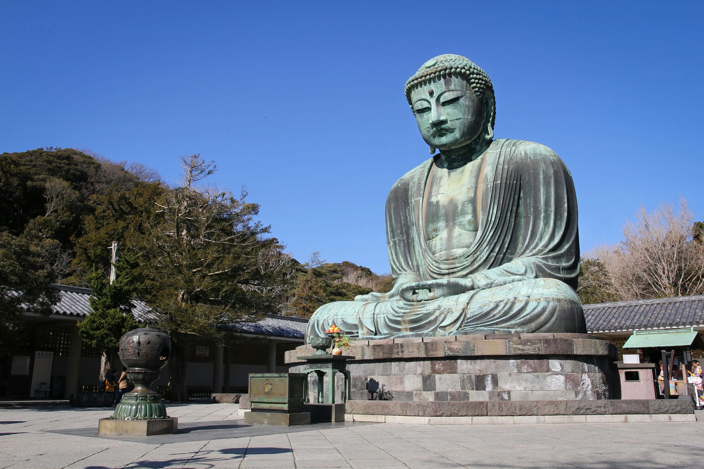 a large green buddha statue is in a courtyard