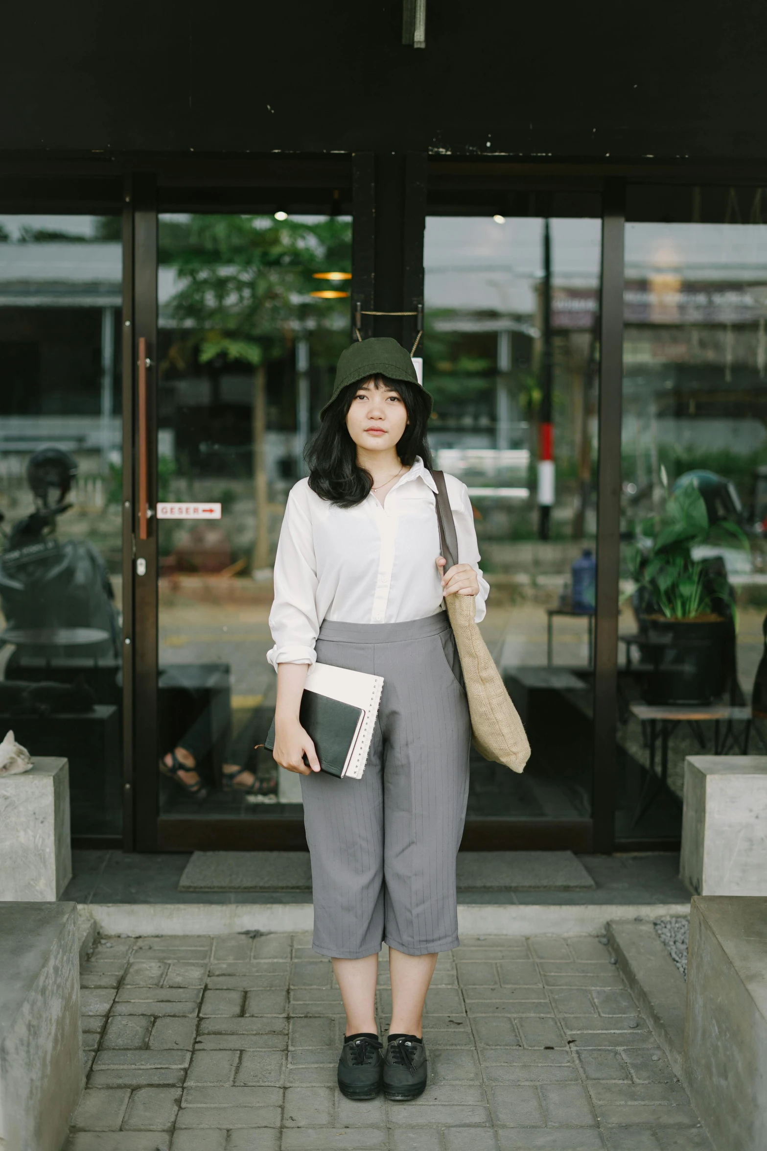 a woman standing on the pavement holding three bags and posing for a picture