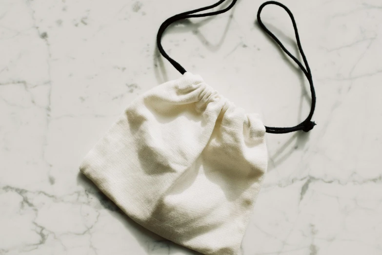 the white pouch bag is sitting on the marble floor