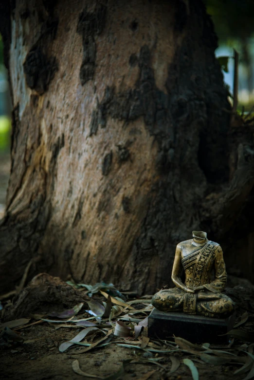 a small statue in front of a large tree