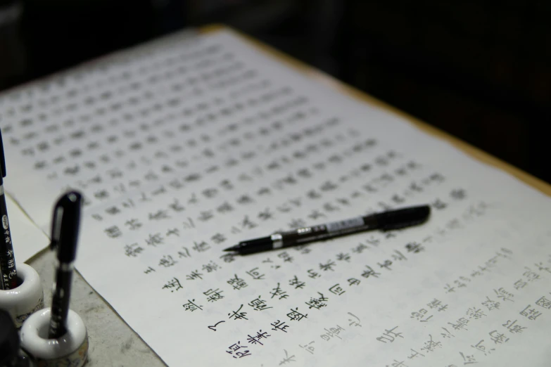 a pen on an open pad with chinese characters written in cursive writing