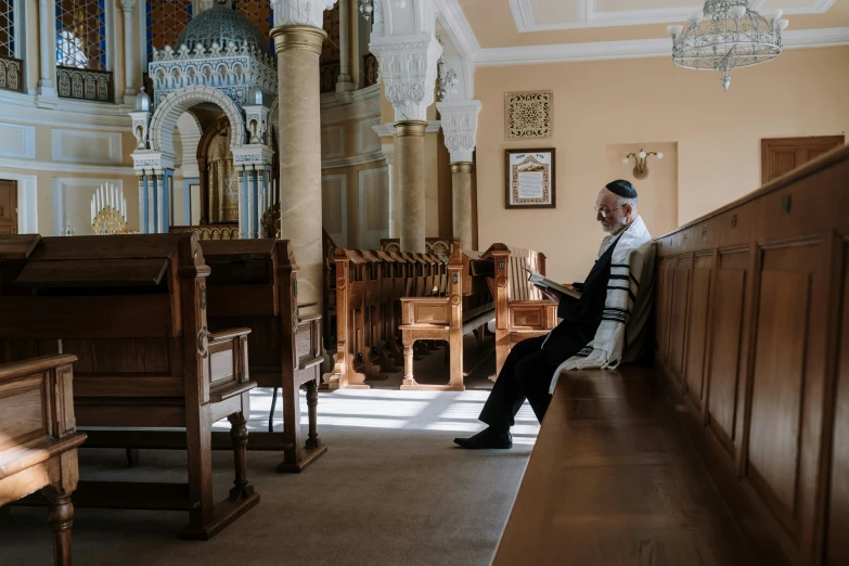 a man sitting on the bench next to a pew in a church