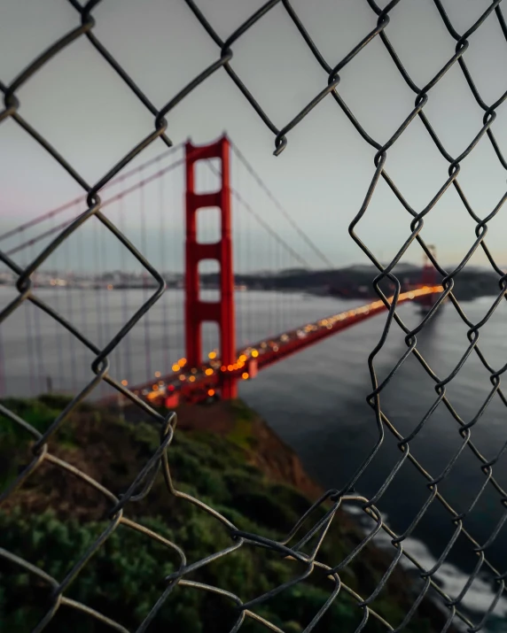 the golden gate bridge as seen through a fence