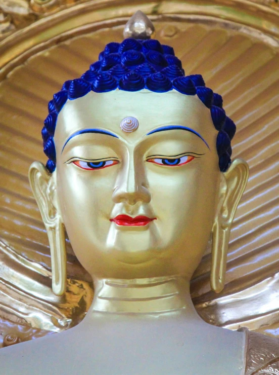 a buddha head on display with blue and red paint