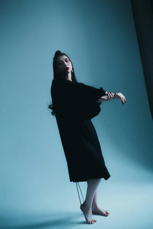 woman with arm stretched out standing against light blue backdrop