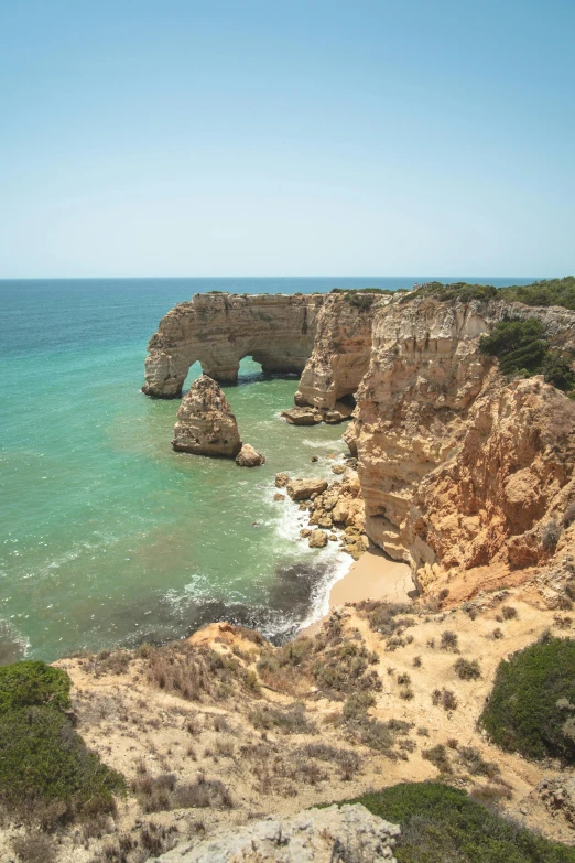 an ocean scene shows rocky coastline and arch