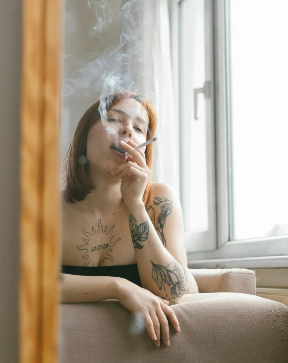 a woman sitting on a couch with a cigarette in her mouth