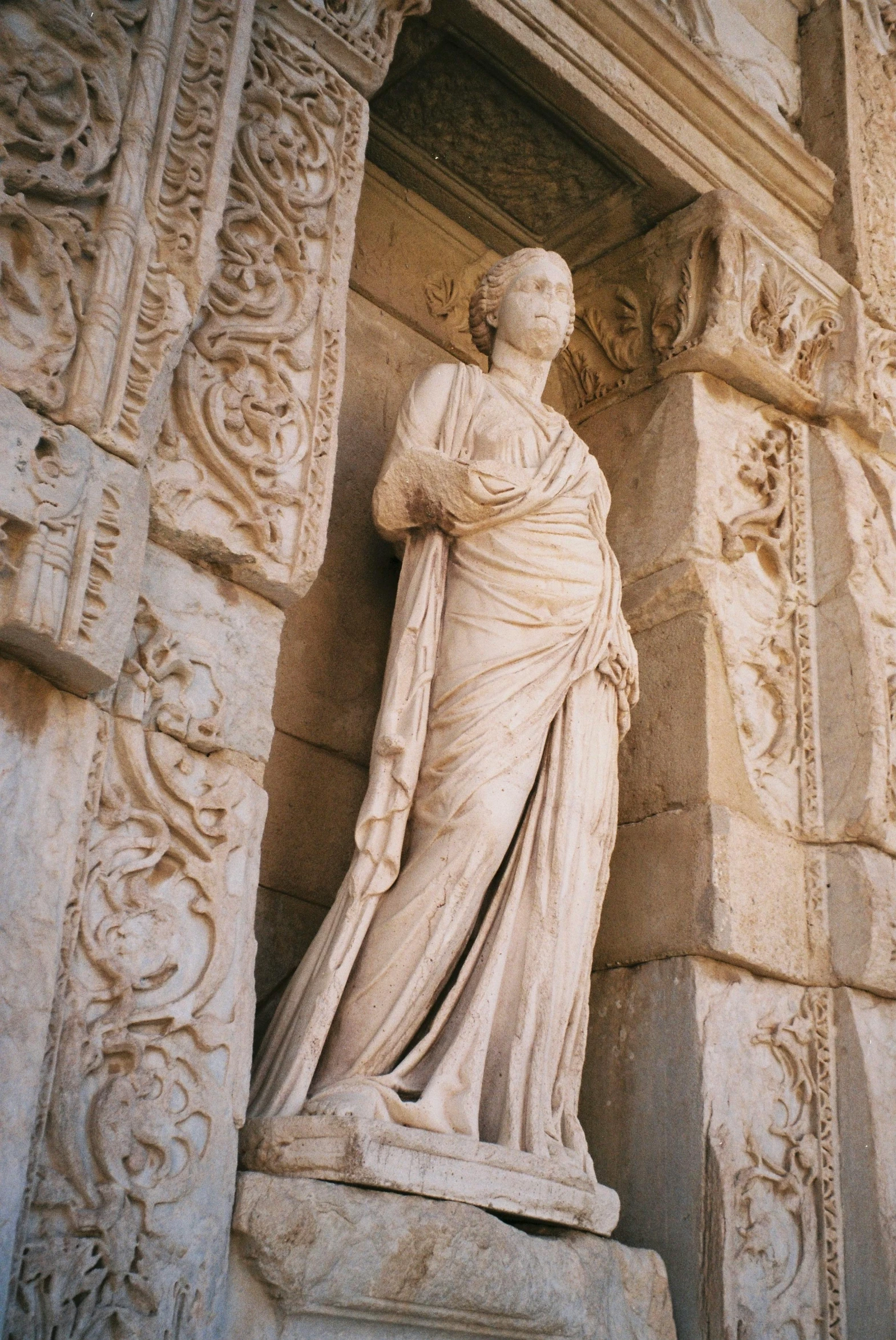 an artistic sculpture of a woman leaning against a building wall