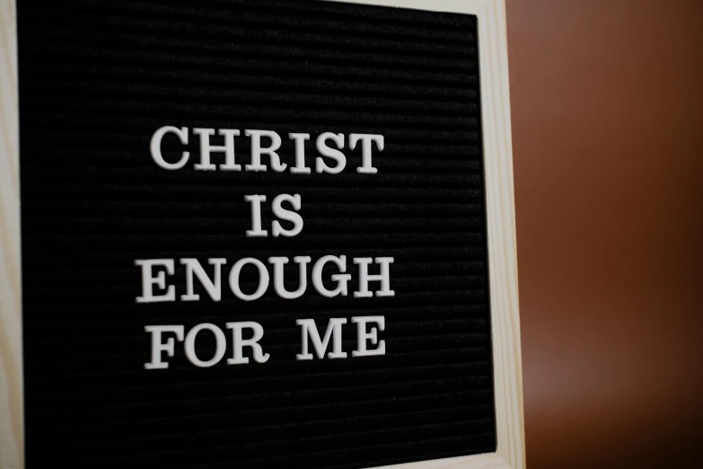 a small square black board with white lettering that reads, christ is enough for me