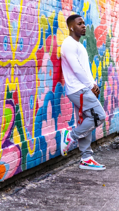 a young man leaning against a colorful wall