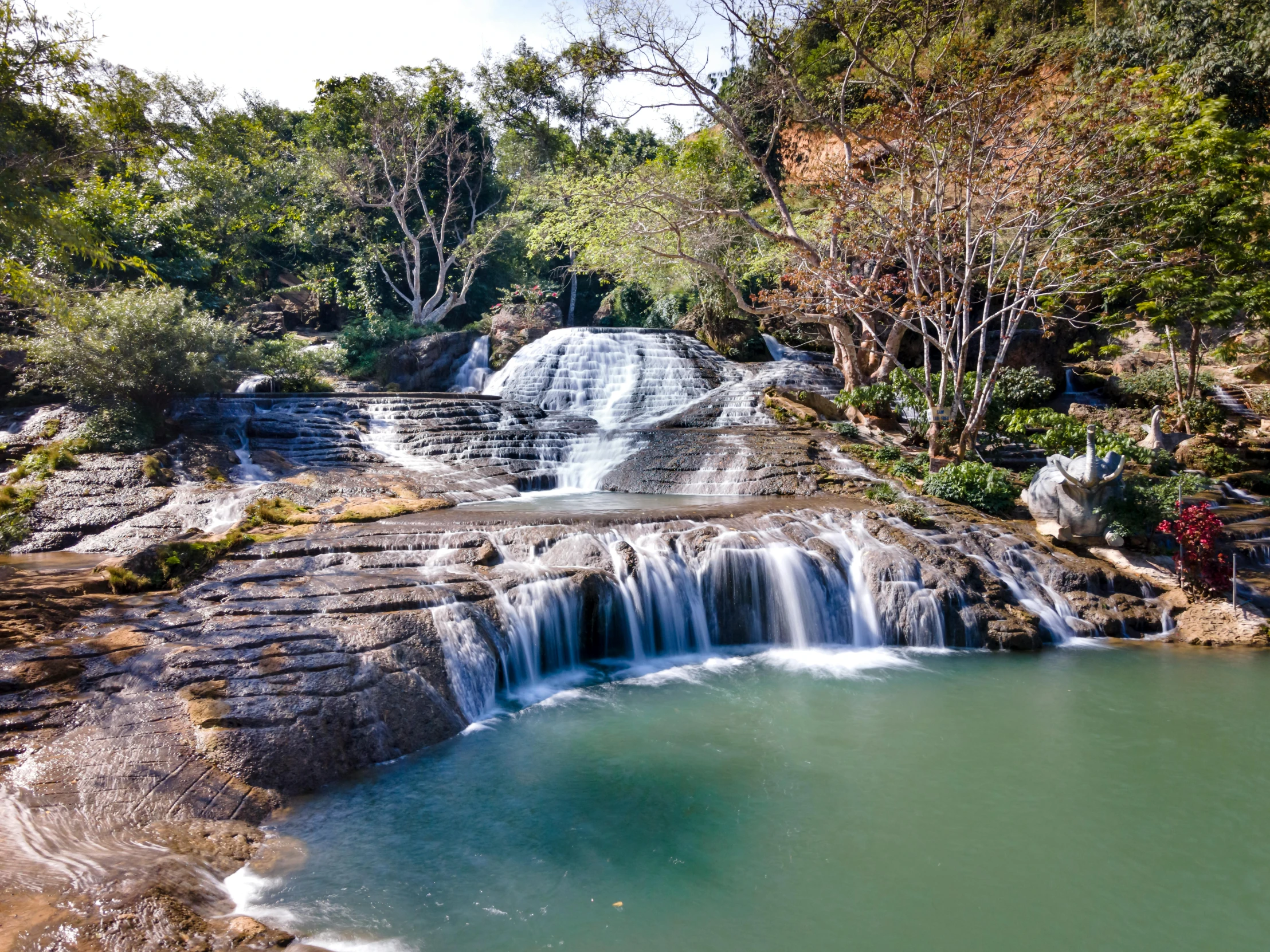 the waterfall has green water that was flowing down it