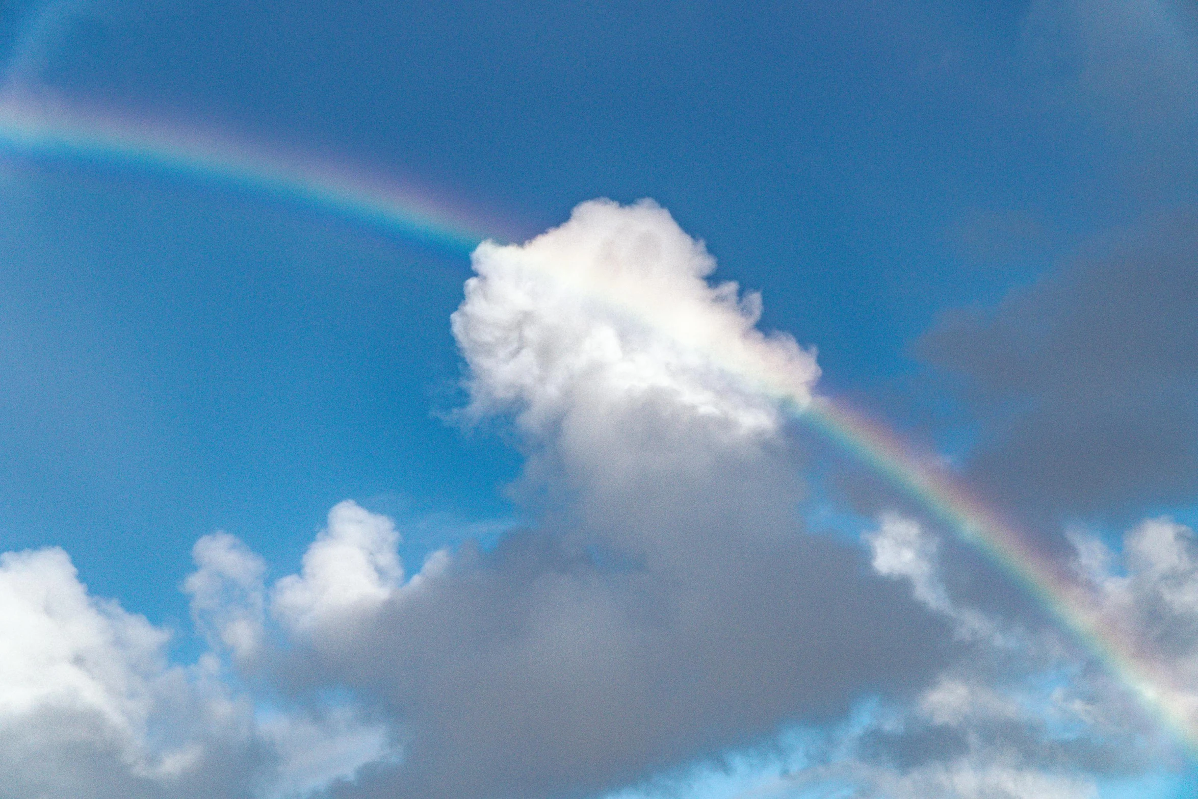 the rainbow is visible over the white clouds