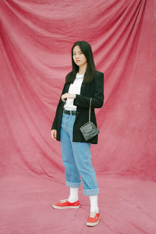 a woman wearing slippers and blazer poses with her handbag