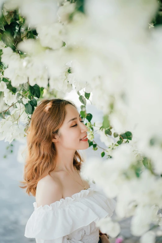 a young woman is looking out at the water under blooming trees