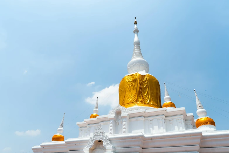 large white and gold building with a yellow buddha statue at the top