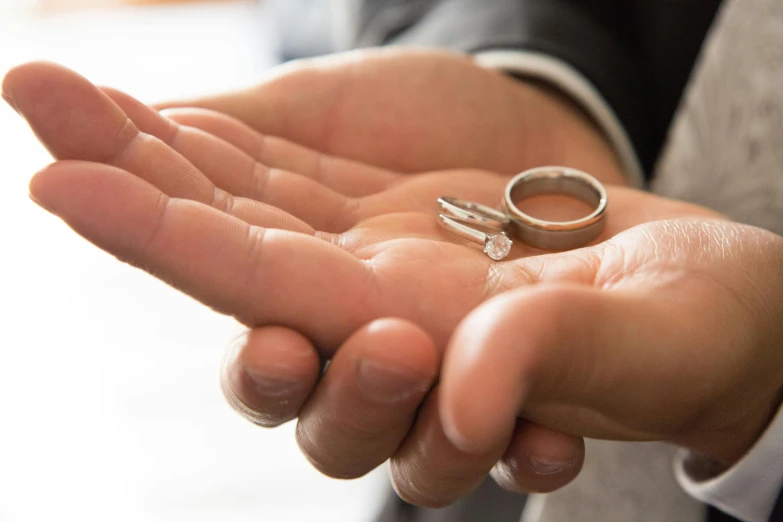 a man holding two wedding rings in his hands