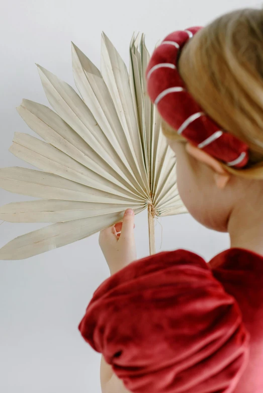  holding up paper fan while looking at it