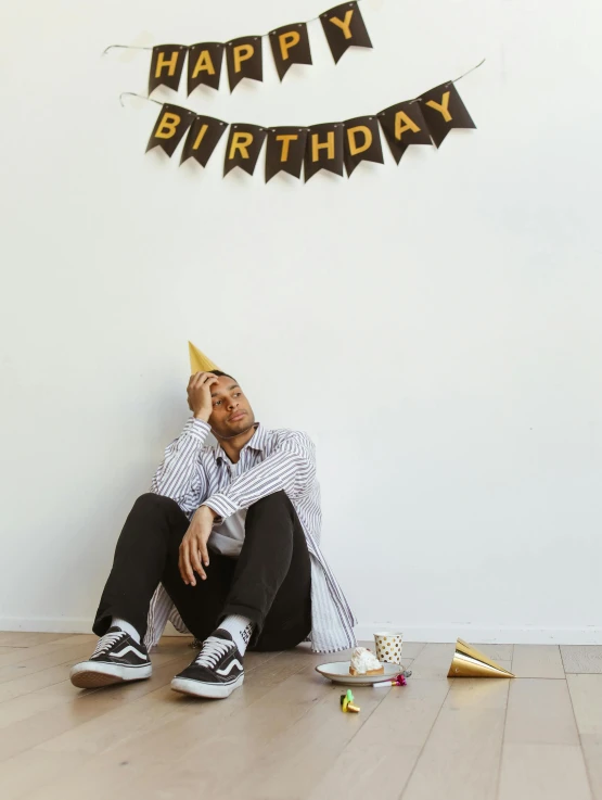 a man sits against the wall while celeting a birthday