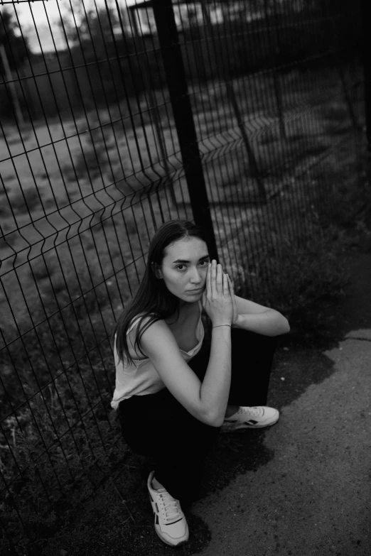 a woman crouching in front of a fence