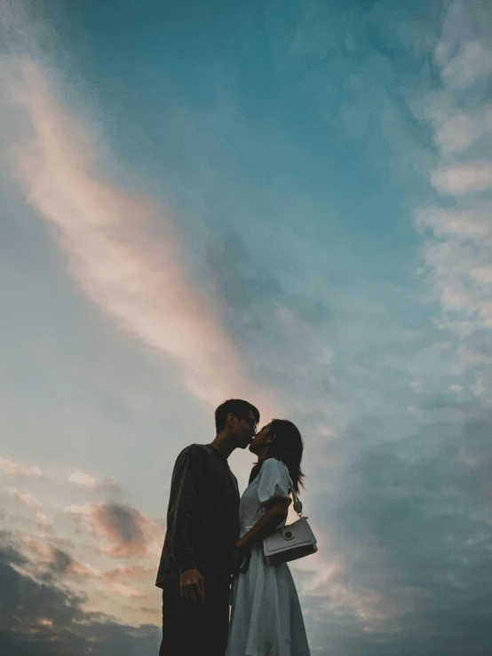 a couple kissing in the sand as the sun sets behind them