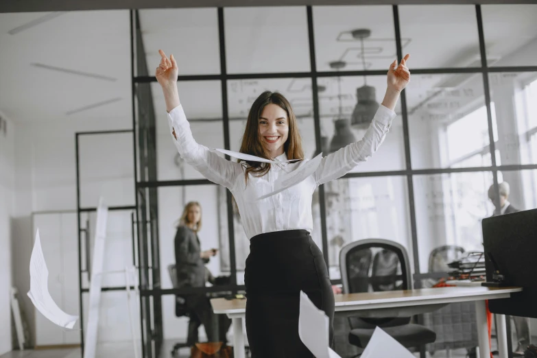 woman in white blouse and black pants in office with hands up