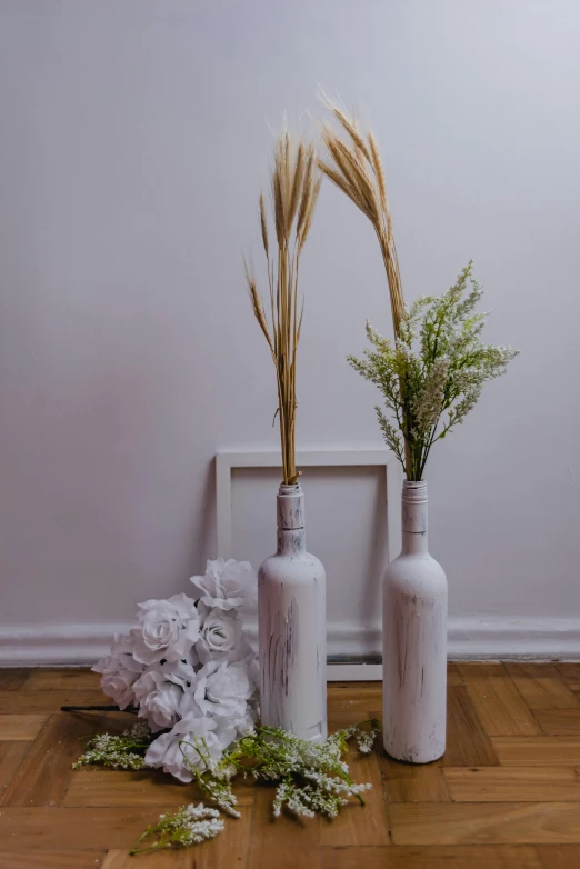 two decorative vases with fake grasses in each one