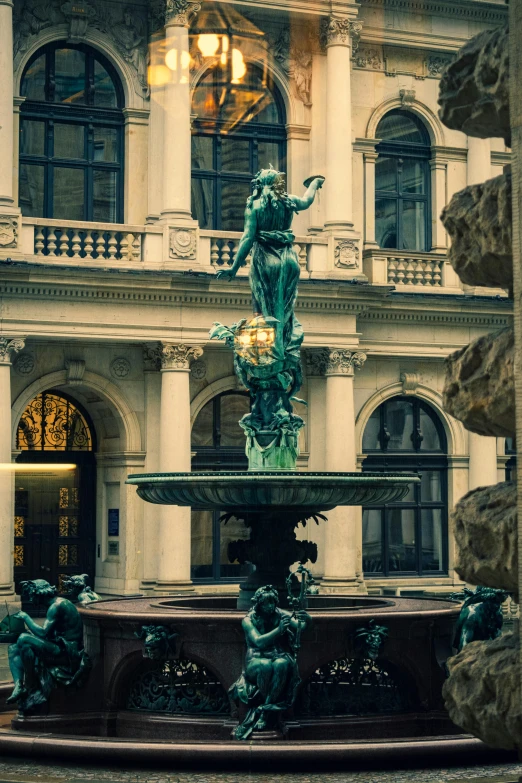 a small fountain surrounded by several statues on a street