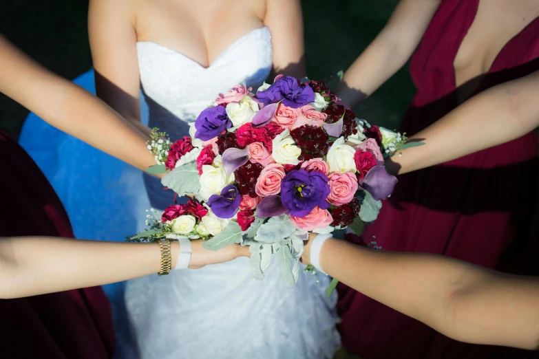 the hands of five women are holding up a bouquet