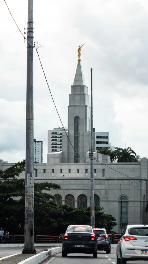 cars drive on the street in front of a very tall church