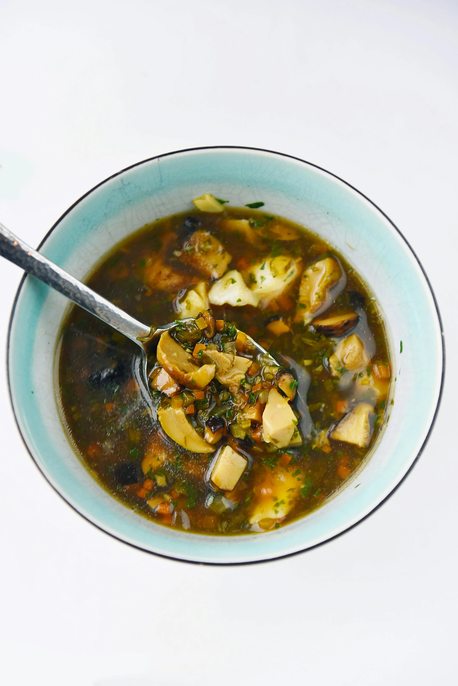 soup in a blue bowl with spoon on white table