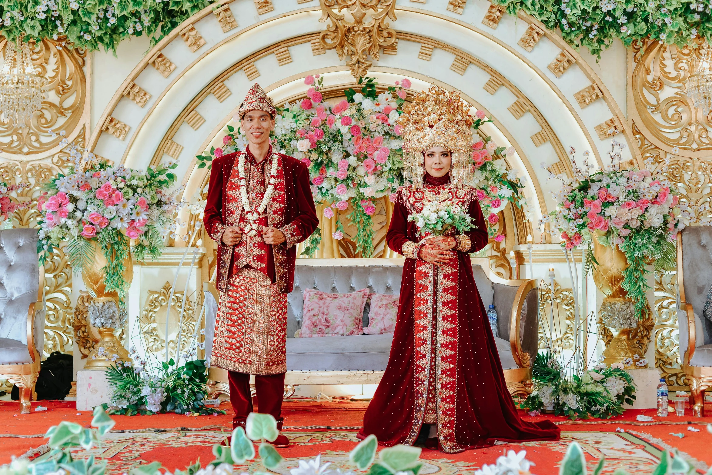 two people in traditional thai dress standing near a wedding decoration