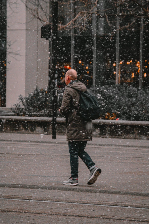 there is a man that is walking down the street in a snowy day