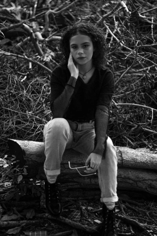 a woman is sitting on a log in the forest