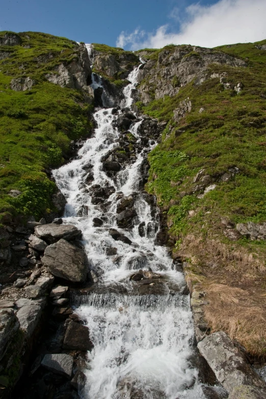 a water fall with a very steep hill in the background