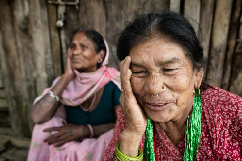 an old lady with a green necklace holding her head