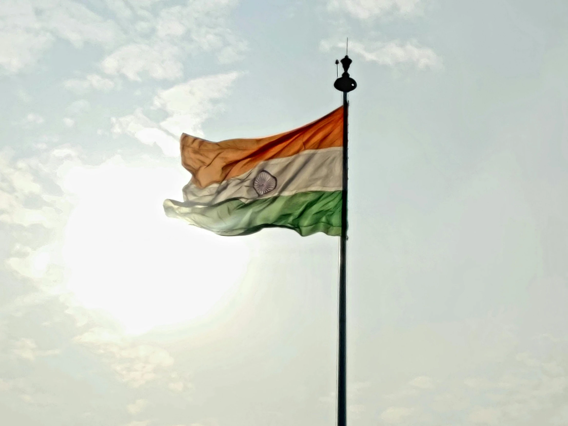 the indian flag is flying on a pole against a blue sky