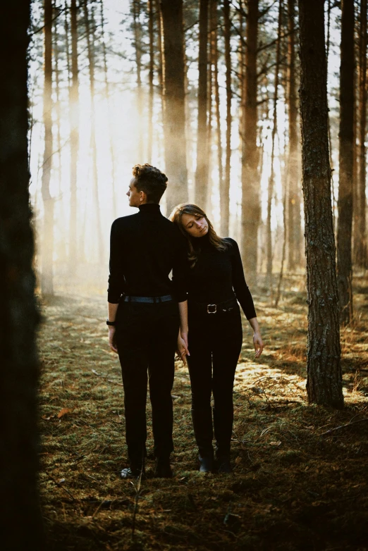 two people in black clothes are standing in the woods