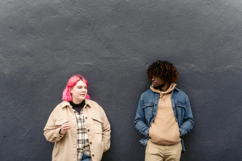 two woman with pink hair are standing next to a wall