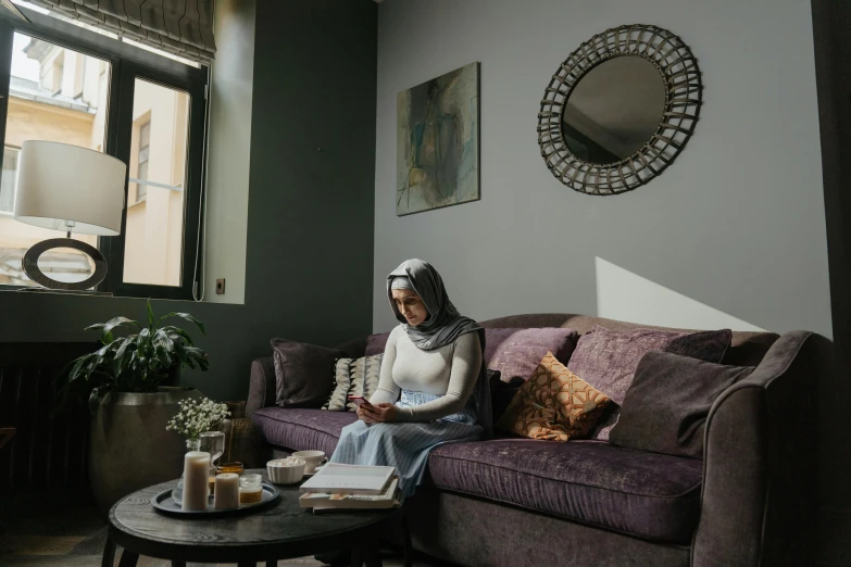 a woman sitting on a couch in the middle of a room with a coffee table