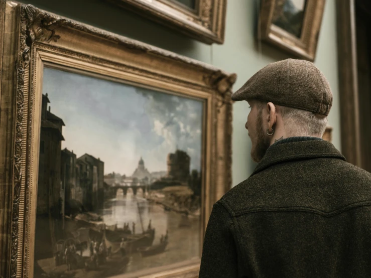 man standing next to painting in historical style with cityscape on wall