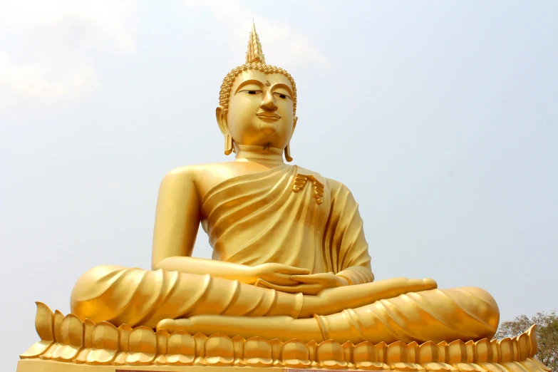 a statue of a sitting buddha in front of a clear blue sky