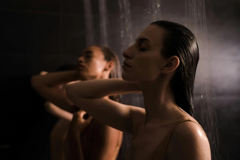 two women are in the shower and one woman is listening to her ear